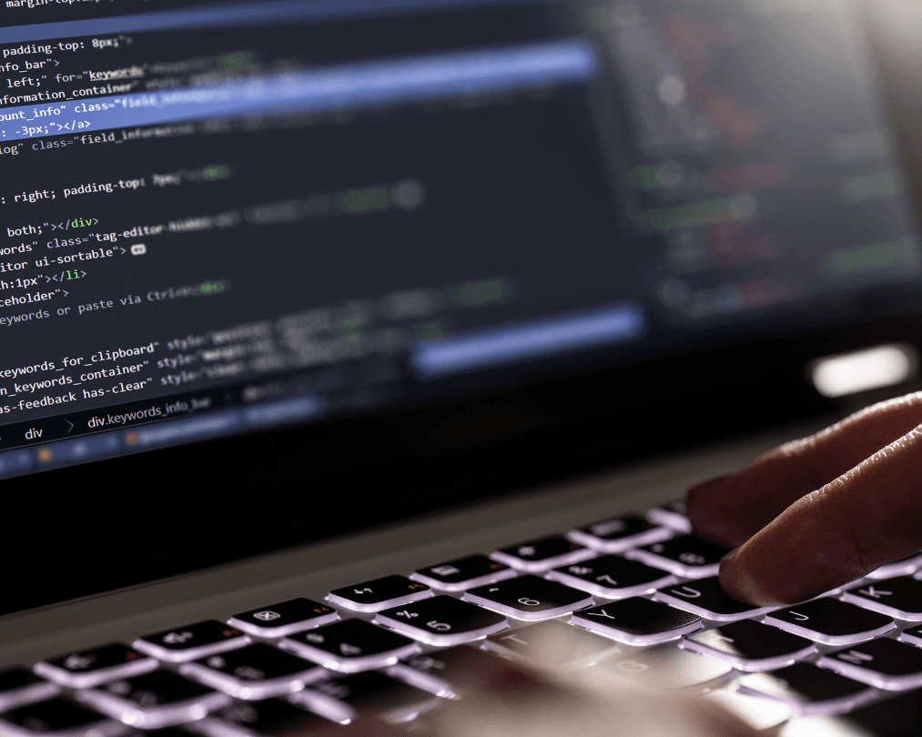 Mãos digitando em um notebook com código de programação na tela